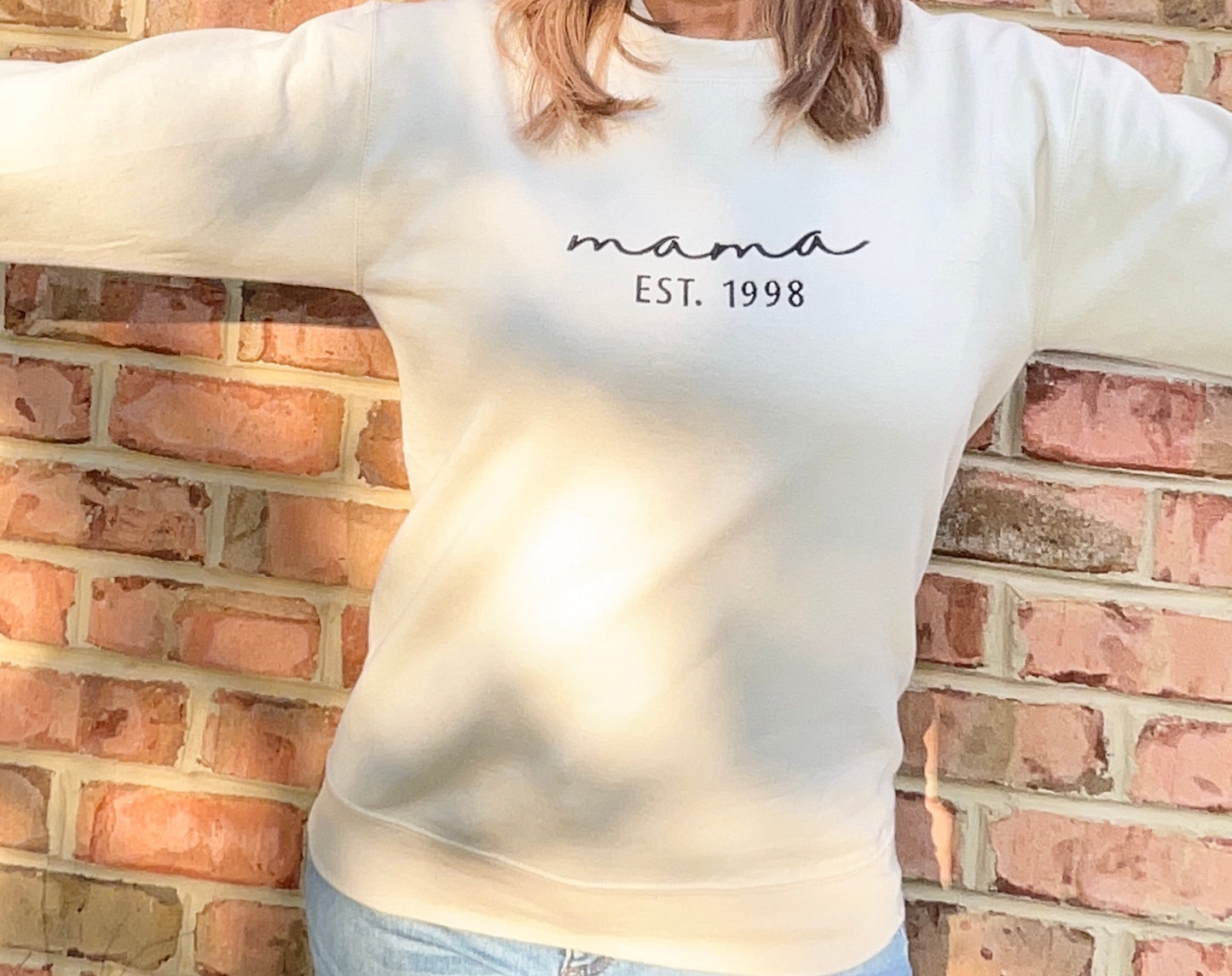 Woman wearing sand colored Mama Sweatshirt with kids Names